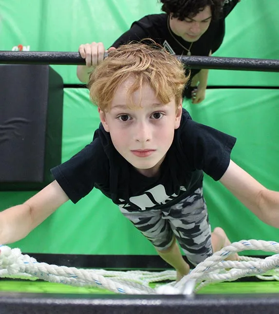 A young ninja climbing through the PEGA obstacle course